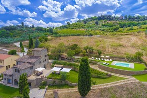 Une villa avec piscine, entourée de jardins luxuriants et de vignobles.