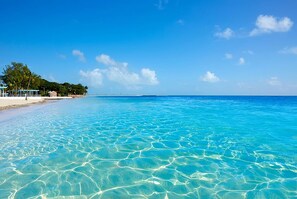 A beach with clear turquoise water, a sandy shore, and a few structures on the left. - Marathon Family Retreat:  Pool, Hot Tub & Outdoor Movie Theater (Marathon)