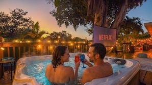 A couple in a hot tub with a Netflix sign in the background.