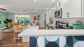 A modern kitchen with white cabinets, stainless steel appliances, and a central island.
