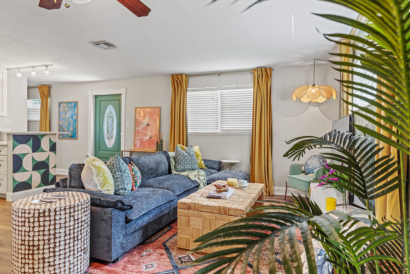 A living room with a blue sofa, patterned cushions, a round coffee table, and a large plant.
