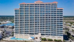 A multi-story hotel with a pool area, surrounded by a landscaped garden and a clear view of the beach. - BEACHFRONT, ZERO ENTRY POOL, PRIVATE BALCONY! (Gulf Shores)