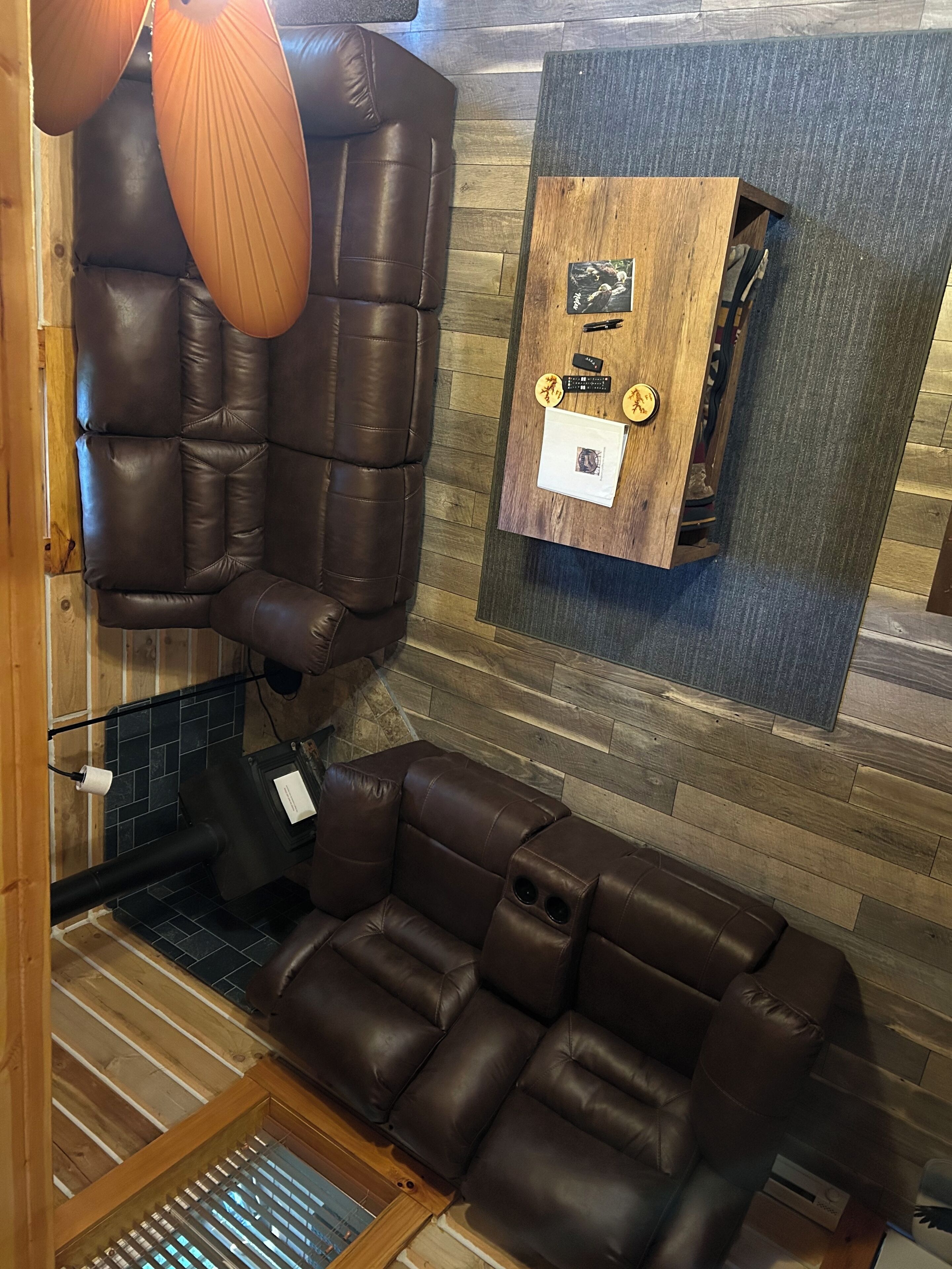 Een moderne, goed verlichte kamer met een leren bank, een houten kast met persoonlijke spullen, en een opvallend plafondontwerp.