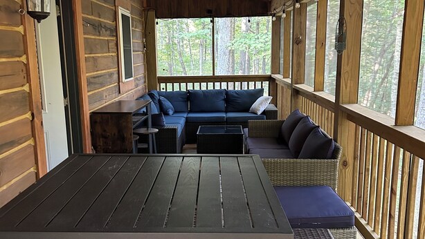 A wooden deck with a table and chairs, a sofa, and a ceiling fan.