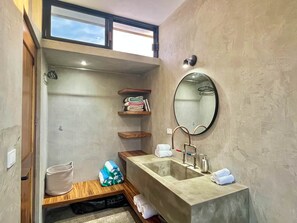 Une petite salle de bain dotée d’un grand lavabo, d’étagères en bois, d’un miroir et d’un porte-serviettes.