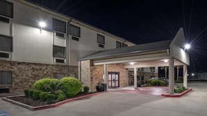 A hotel entrance with a covered waiting area, stone facade, and well-maintained landscaping.