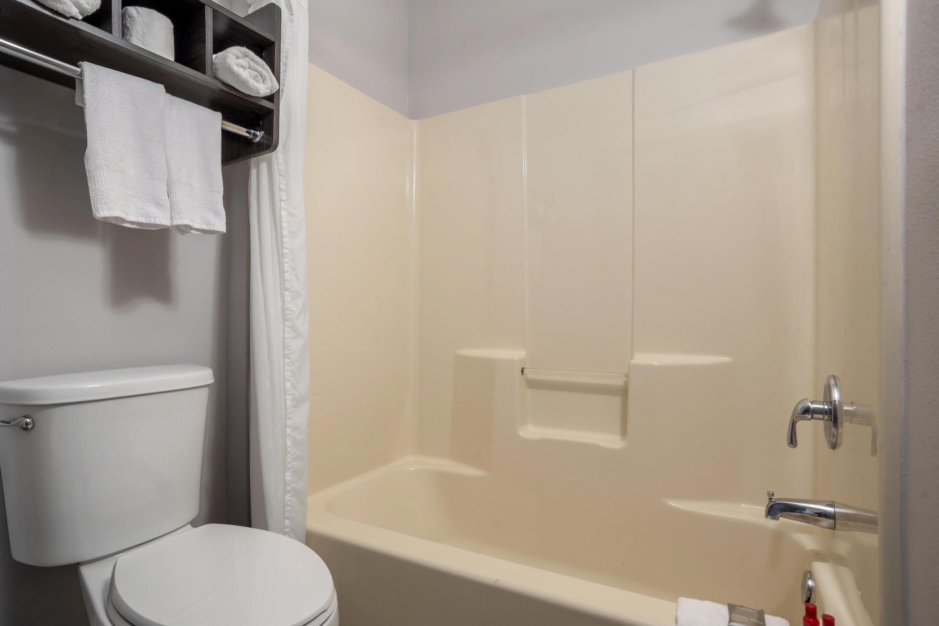 Une salle de bain équipée de toilettes, d’une baignoire et d’un porte-serviettes avec des serviettes.