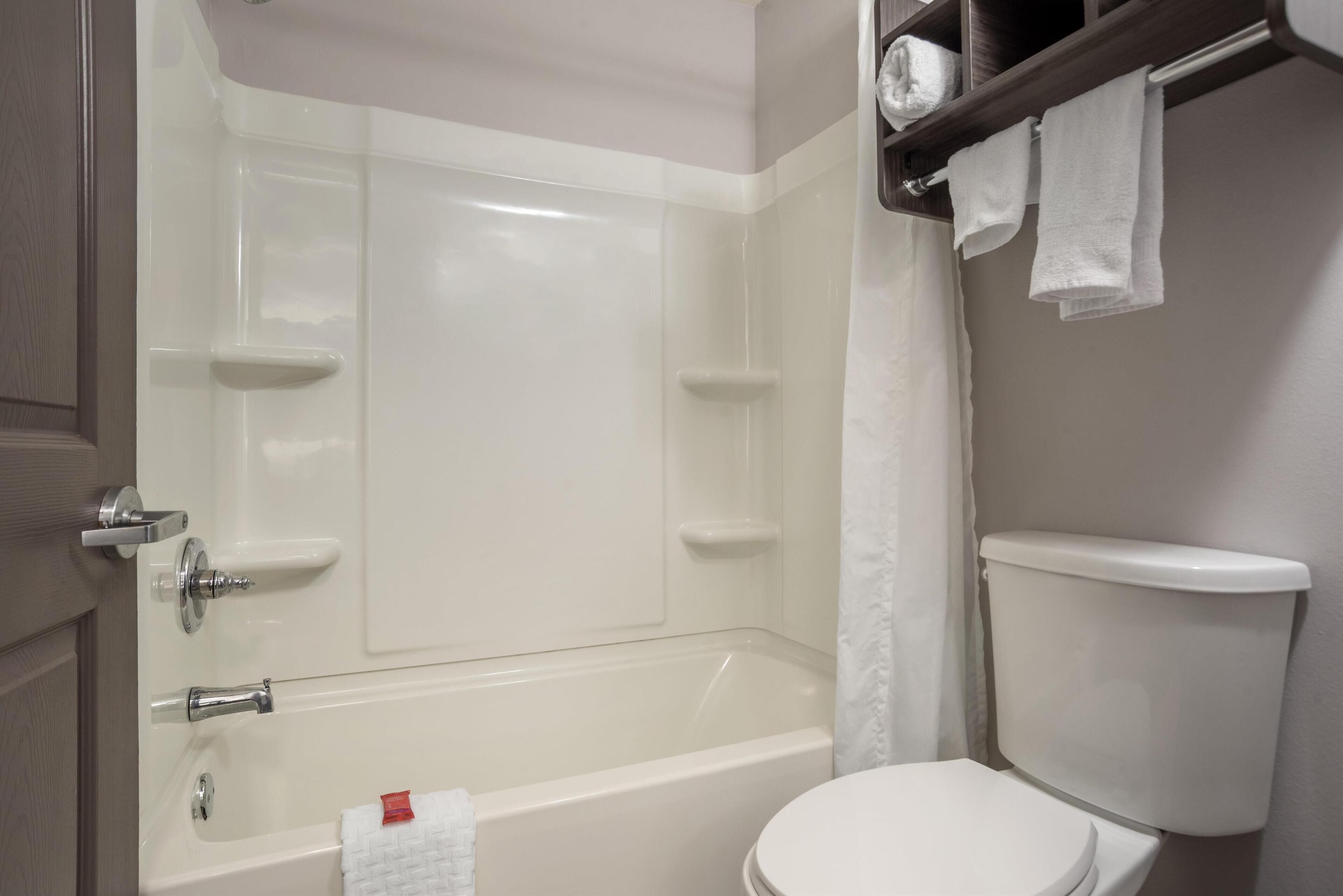 A bathroom with a white bathtub, a toilet, and a towel rack with towels.