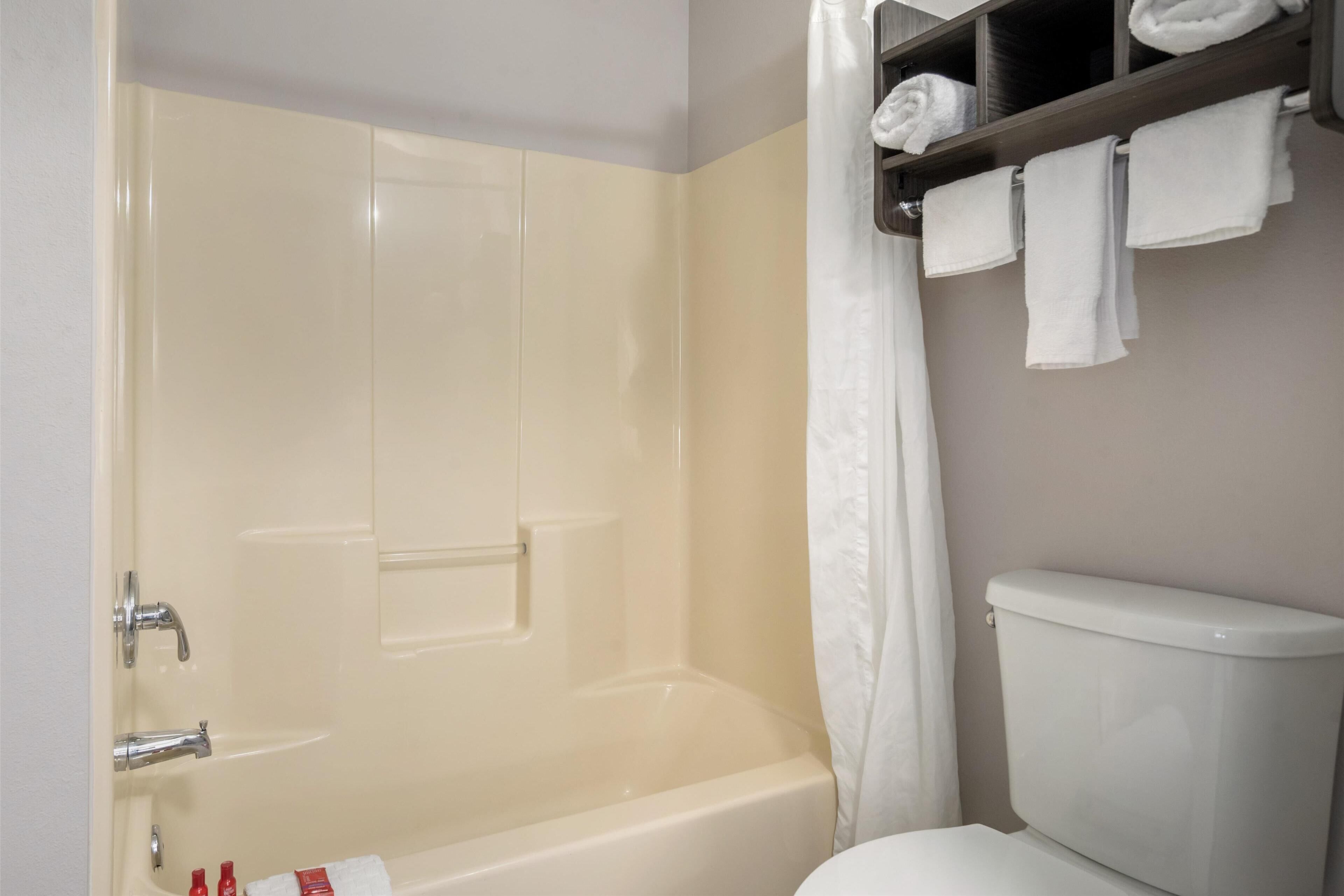 Ein Badezimmer mit Badewanne, Toilette und Regalen mit Handtüchern.