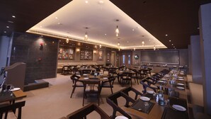 A spacious restaurant with multiple dining tables and chairs, a high ceiling with recessed lighting, and a modern interior design. - Surestay By Best Western Lucknow (Lucknow)