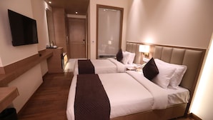 A hotel room with two beds, a TV, a mirror, and a wooden floor. - Surestay By Best Western Lucknow (Lucknow)