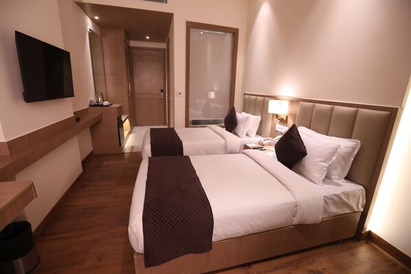A hotel room with two beds, a TV, a mirror, and a wooden floor. - Surestay By Best Western Lucknow (Lucknow)