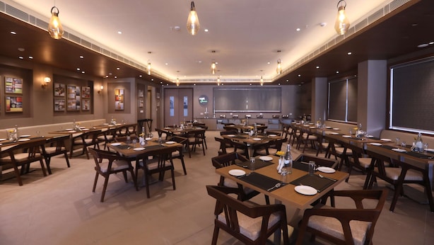 A spacious dining area with multiple tables and chairs, equipped with place settings and ambient lighting. - Surestay By Best Western Lucknow (Lucknow)