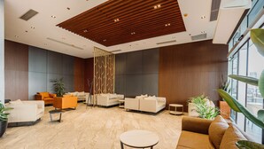 A modern lobby with a marble floor, sofas, a coffee table, and large windows offering a city view. - Best Western Plus Batumi (Batumi)
