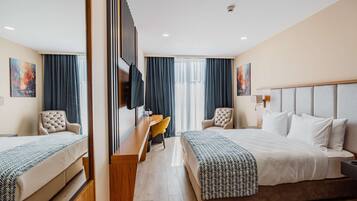 Una habitación de hotel con una cama grande, un escritorio con silla, televisión y una ventana con cortinas.