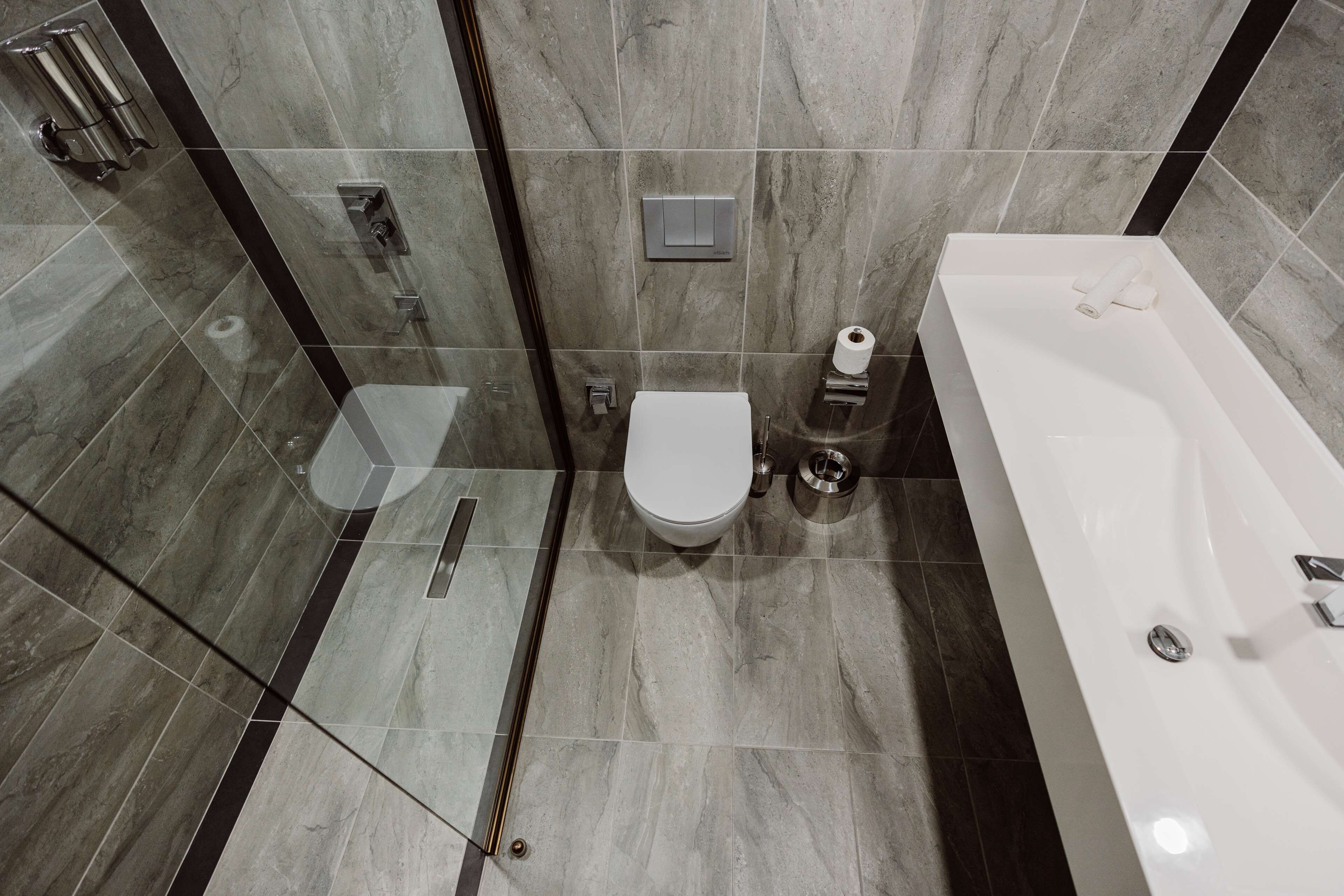 A modern bathroom with a glass shower enclosure, a white toilet, and a bathtub.