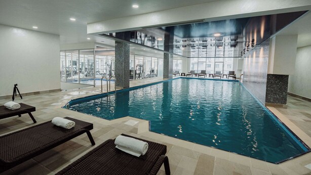 An indoor swimming pool with lounge chairs and exercise equipment. - Best Western Plus Batumi (Batumi)