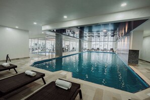 Una piscina interior con sillas de descanso y equipo de ejercicio.