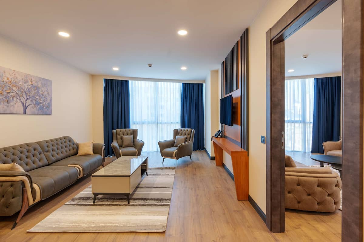 A modern living room with a sofa, armchairs, a coffee table, and a TV.