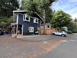 A two-story house with a porch, a swing chair, and a car parked in the driveway. - Welcome Kye Bay Nest at  the beach - relax, restore, and explore. H820823952 (Comox)