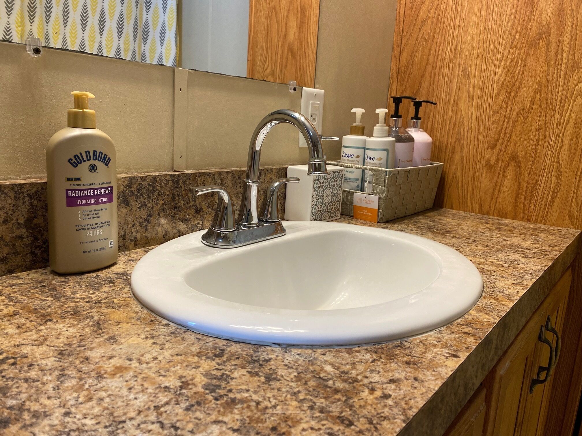 Un bagno con un lavandino bianco, uno specchio e articoli da toilette sul ripiano.