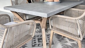 A dining area with a large rectangular table, wicker chairs, and a patterned rug. - Birch Bayside Retreat - AC, Pet Friendly & Close to the Beach! Luxury 2 Bedroom (Blaine)