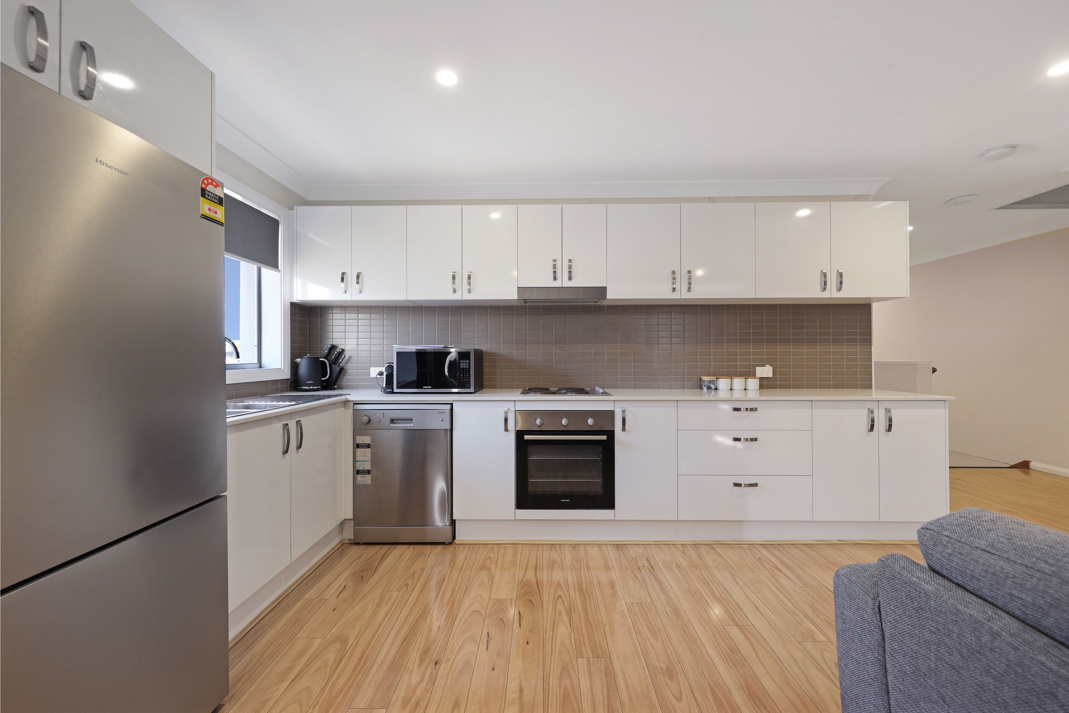 A modern kitchen with stainless steel appliances, white cabinetry, and a tiled backsplash.