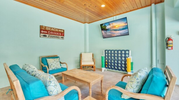 Ein Zimmer mit Holzbalkendecke, einem an der Wand montierten Fernseher, einem Schild mit den Hinweisen Strand, Getränke und Angeln sowie einem Feuerlöscher.