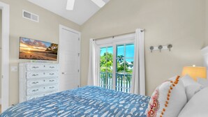 Ein Schlafzimmer mit Bett, Fernseher, Kommode und einem Balkon mit Blick.