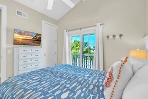 A bedroom with a bed, a TV, a dresser, and a balcony with a view. - Jersey Girl by Duncan Real Estate (Anna Maria)
