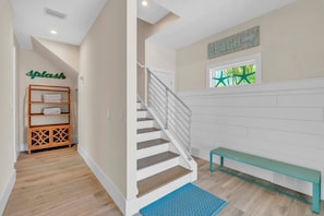A staircase with a metal railing, a wooden bench, and a wall-mounted sign that reads "BEACH". - Jersey Girl by Duncan Real Estate (Anna Maria)