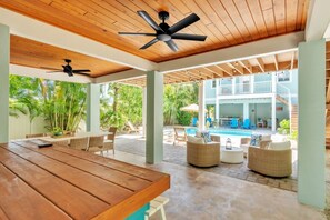Ein überdachter Außenbereich mit Pool, Korbmöbeln und Deckenventilatoren.