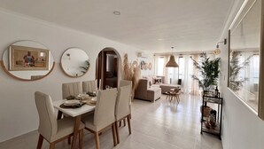 Uma sala de jantar moderna com uma mesa redonda, cadeiras e vista para a sala de estar.