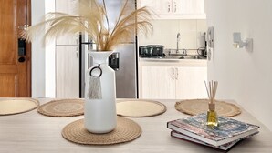 Uma cozinha moderna com uma geladeira de aço inoxidável, um vaso branco com plumas de capim-do-campo e um livro sobre o balcão.