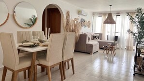 Uma sala de estar moderna com área de jantar, apresentando um sofá, uma mesa de centro e uma mesa de jantar posta para quatro pessoas.