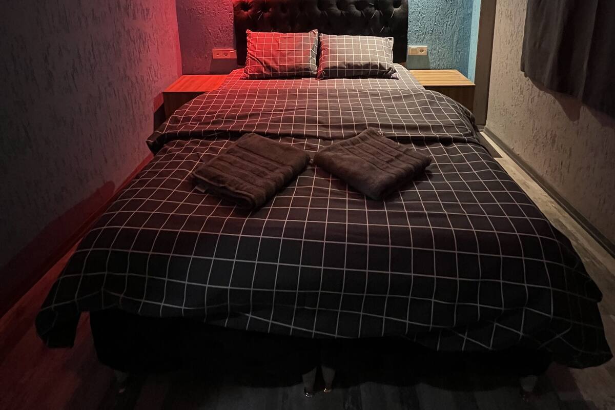 A bedroom with a bed, pillows, and a nightstand.