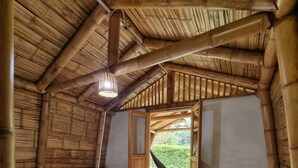 A room with a wooden ceiling, a bed, a small table, and a view of greenery outside. - Pradera Ecoliving (Betania)