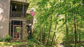 A two-story house with a stone facade, a red door, and an American flag. - Heavenfell | Spacious Montreat Home | 1 Mile from Lake Susan & Conference Center! (Montreat)