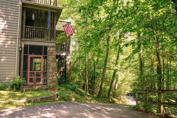 Une maison à deux étages avec une façade en pierre, une porte rouge et un drapeau américain.