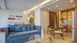 Un salon moderne avec un canapé bleu, une table basse en verre et un coin repas comprenant des chaises en bois et une table en verre.