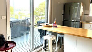 Eine moderne Küche mit einer großen Schiebeglasdoor zum Balkon, einem Kühlschrank und einer Holzarbeitsplatte.