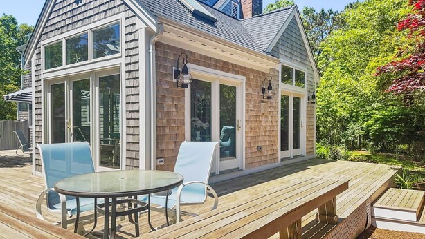 A house with a deck, a covered patio, and a large window overlooking a garden. - Sandy Spot: Walk to Beach, Sleeps 10 (Harwich Port)