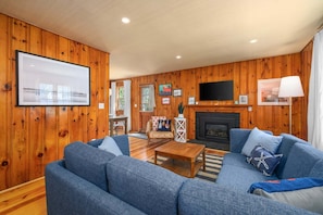 A living room with a sofa, coffee table, fireplace, TV, and wooden walls.