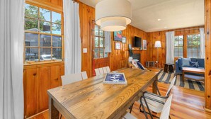 A wooden-paneled room with a dining table, chairs, a sofa, and a television.
