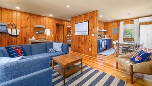 A wooden interior with a sofa, a coffee table, a dining table, and a kitchen area.