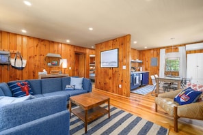 A wooden interior with a sofa, a coffee table, a dining table, and a kitchen area.