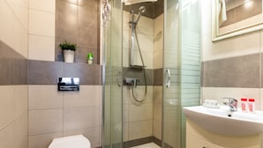 A modern bathroom with a glass-enclosed shower, a toilet, and a sink with toiletries.