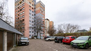 A parking lot with several cars, a multi-story residential building, and a brick building on the left.