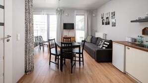 Um apartamento moderno com área de jantar, sofá, cozinha e janelas amplas.