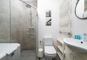 A modern bathroom with a glass shower enclosure, a toilet, and a sink with a mirror. - Wola Burakowska Standard Studio (Warszawa)